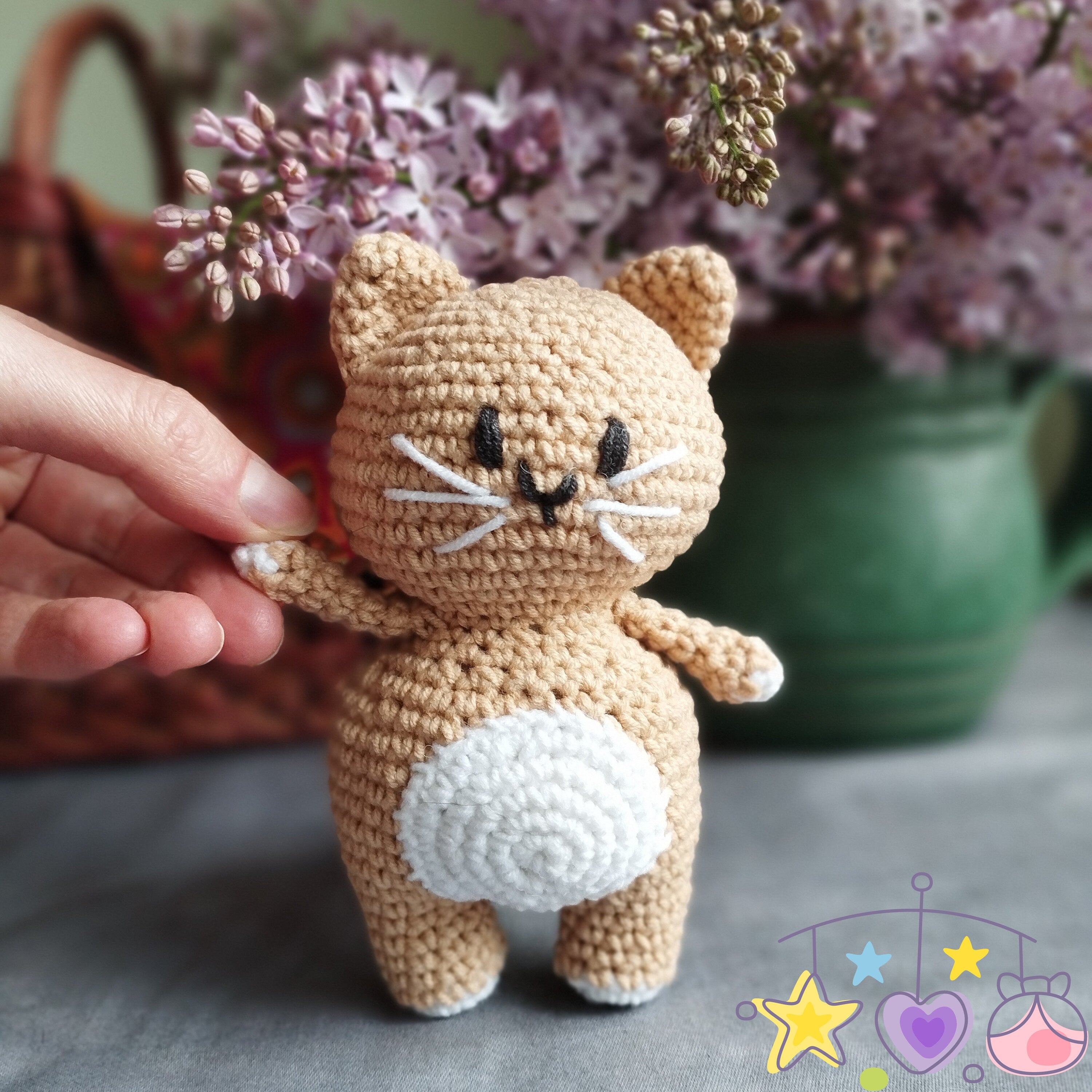 a crocheted cat standing next to a vase of flowers